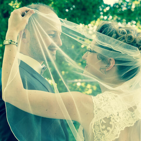 Hochzeitspaar in Nahaufnahme mit Schleier im Vordergrund