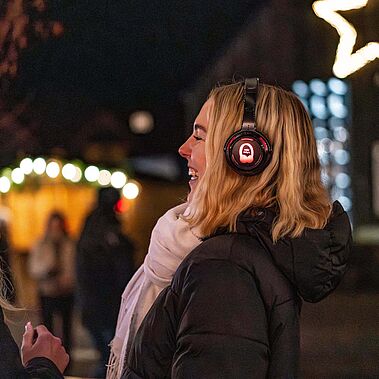 Zwei junge Frauen mit Kopfhörern vor weihnachtlicher Hofkulisse