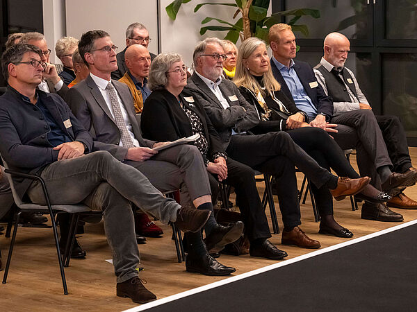 Gäste und Preisträger bei der Ehrenpreisleihung Gäste und Preisträger sitzen in einer Stuhlreihe und schauen auf die Bühne