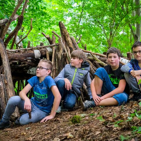 Kinder sitzen auf Waldboden 