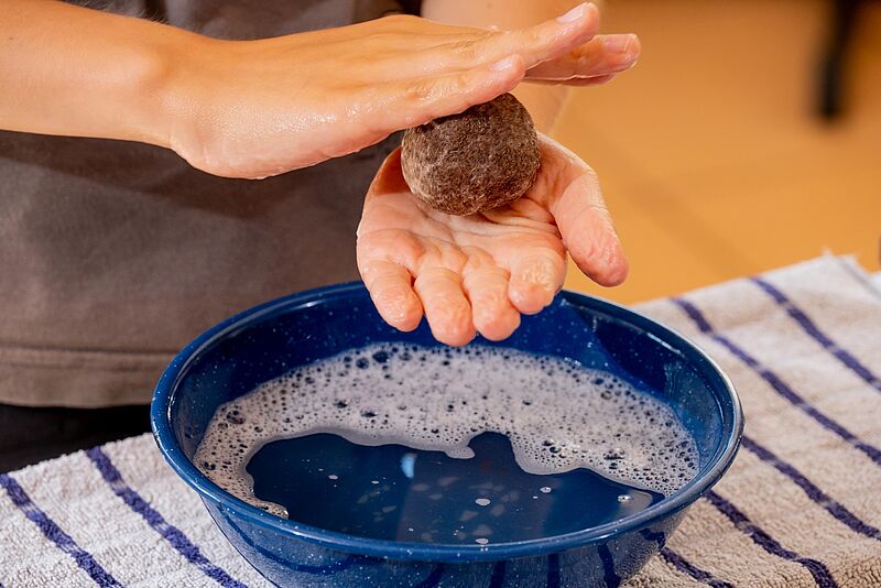 Filzball wird über Wasserschale in den Händen gewendet