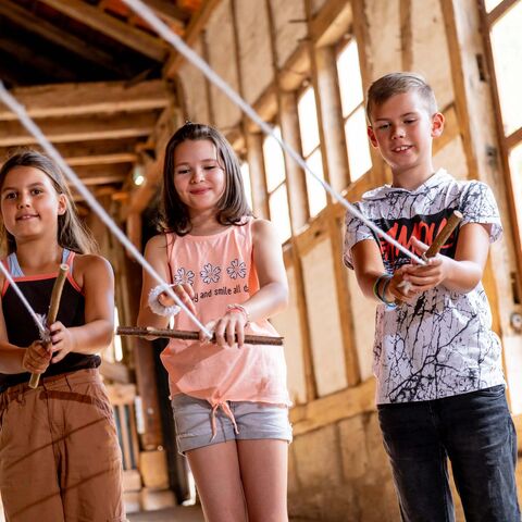 Drei Kinder im Stall drehen Seilstränge