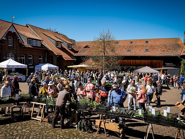 Hofansicht mit Verkaufsständen zum Kräutermarkt Gut Herbigshagen Menschen an einem Kräuterverkaufsstand auf dem Hof von Gut Herbigshagen